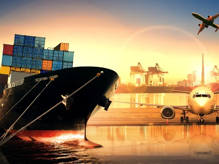 Container ship at sunset with a cargo aircraft overhead